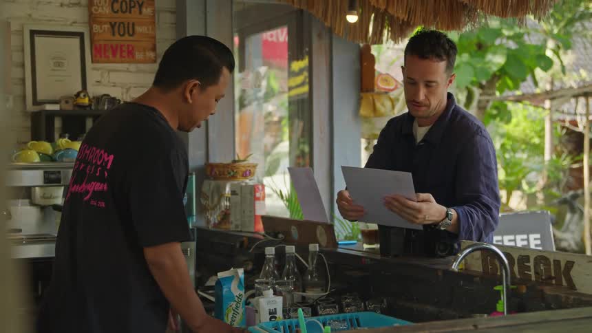 Man uses menu to order while standing in open air cafe