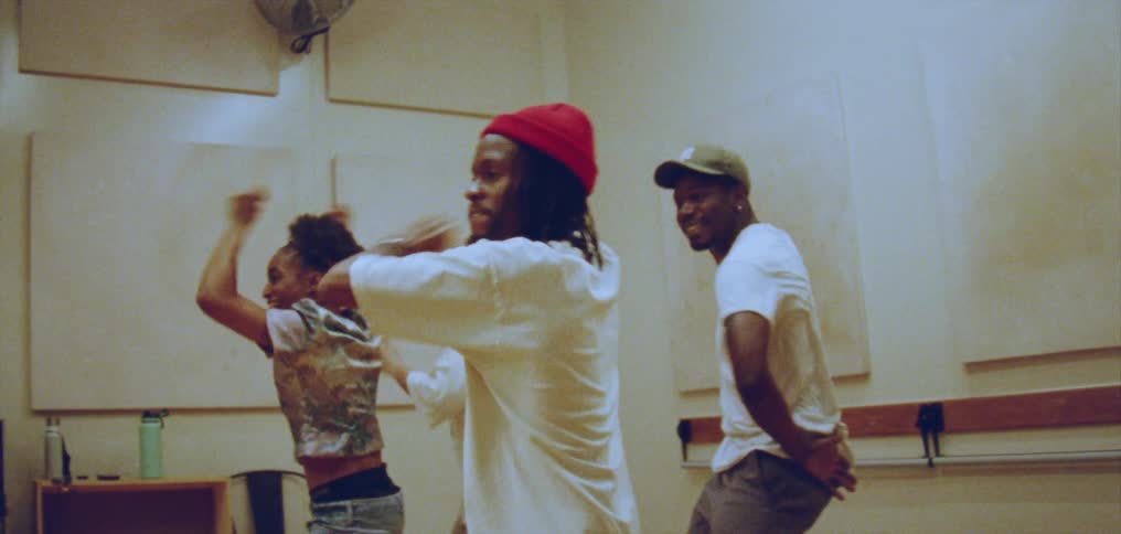 Group of happy people performing a choreographed dance in front of a mirror on a studio