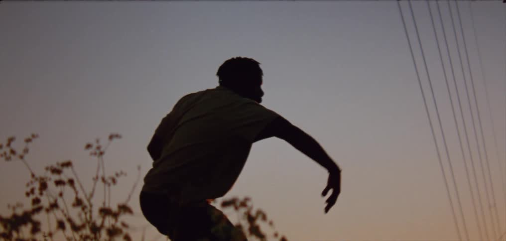 A man dances outdoors at sunset