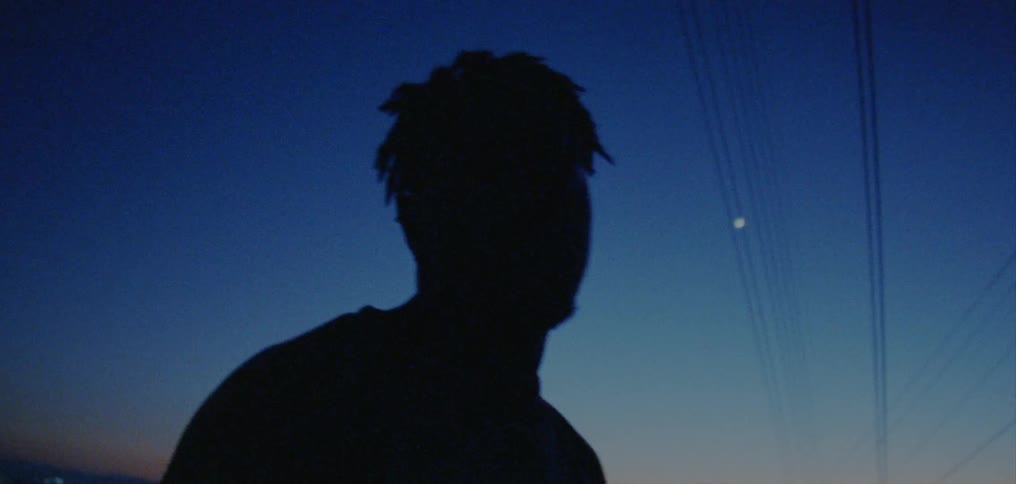 A man sways back and forth while standing outside at night