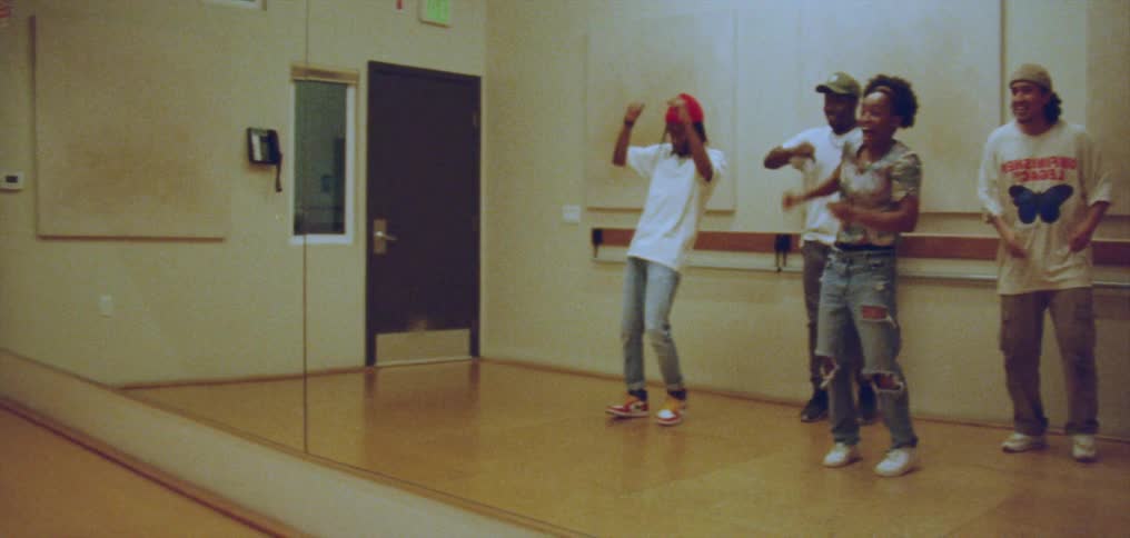 Large dance studio mirror reflects dance group practicing their dance routine