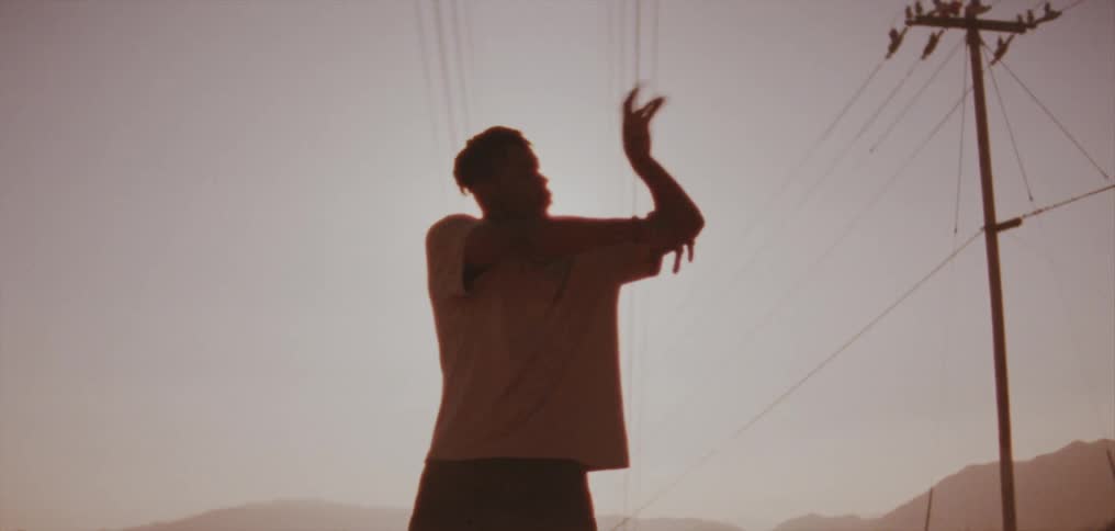 A man dances next to power lines outside