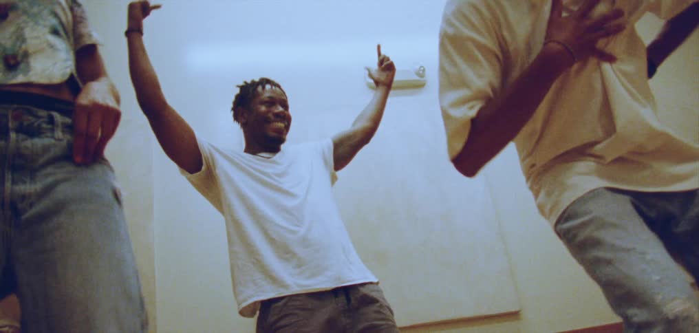 A group of people are in a room dancing and smiling with their arms in the air having a good time