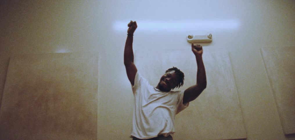 Young happy man wearing a white shirt dances alone energetically on a room