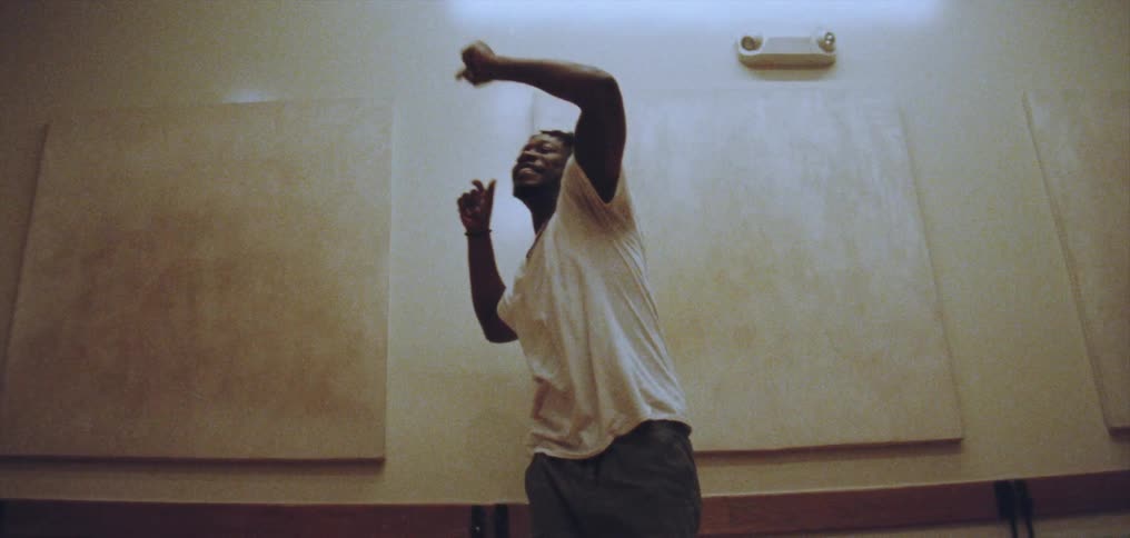 Young happy man wearing a white shirt dances alone energetically on a room