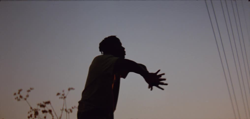 Man dances partly silhouetted against the sky