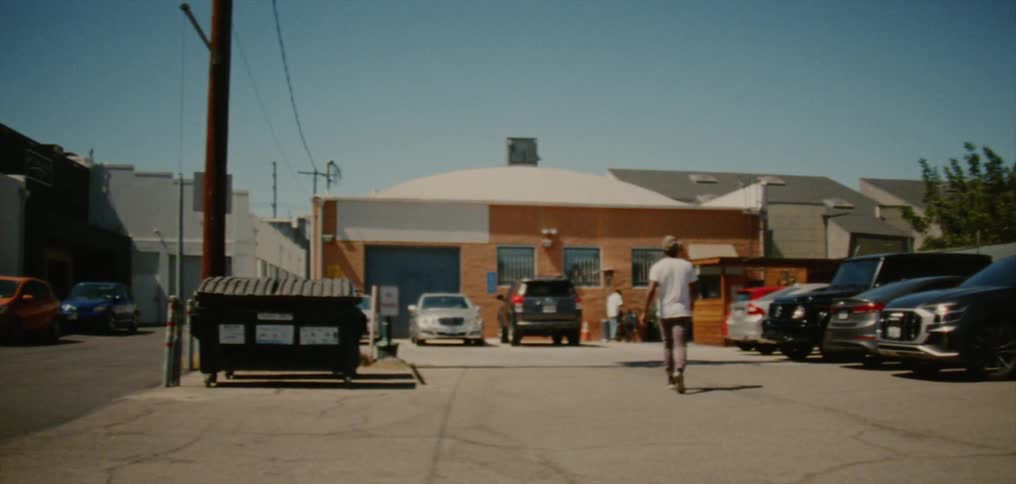 Young man walks on the parking lot of a small town store at daytime caught on vintage film