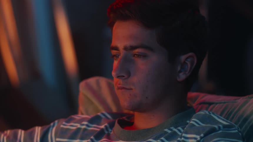 Media reflects onto mans face while he sits viewing