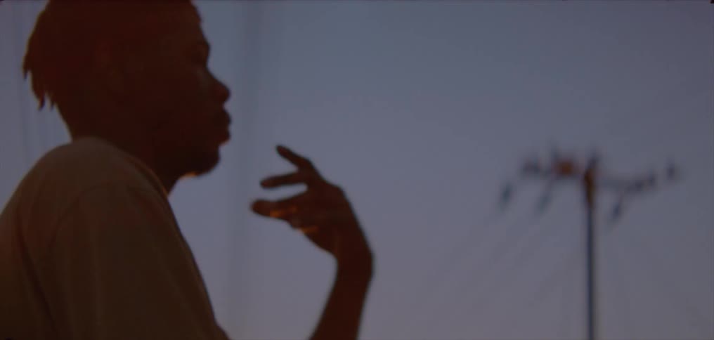 Young man slowly waves his hands on the countryside at evening