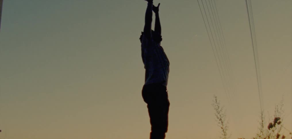 The silhouette of a young man reaching for the sky as he dances