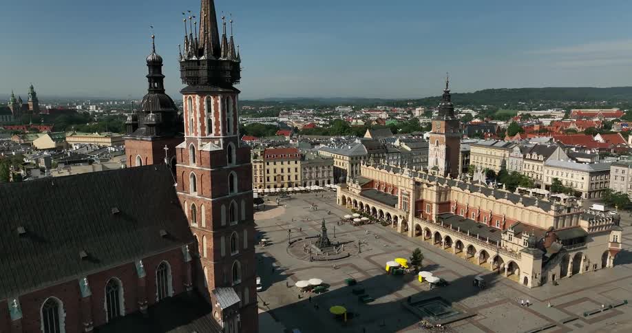 People mill about a town square near a monument and government buildings