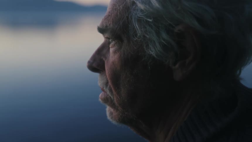 The man is looking out over the lake
