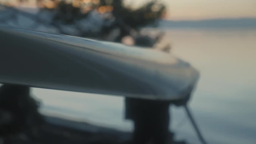 A person carries a kayak down to the water