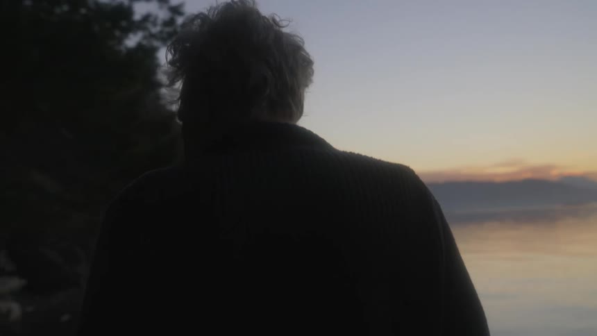 A man turns from the lake