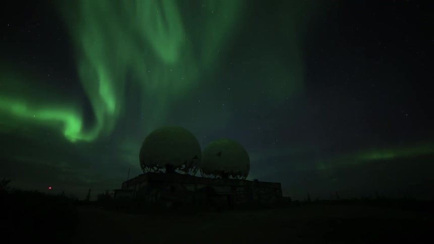 The green glow of the northern lights shines as the aurora borealis moves over an observatory