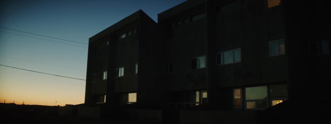 A pair of apartment buildings are located next to each other as the sun is beneath the horizon