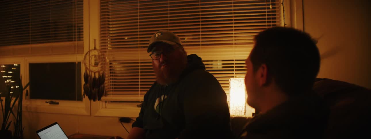 Two men in conversation while sitting in doors at night