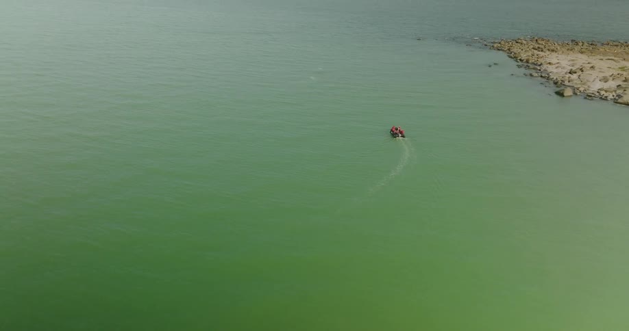 The motor boat is driving past the shore