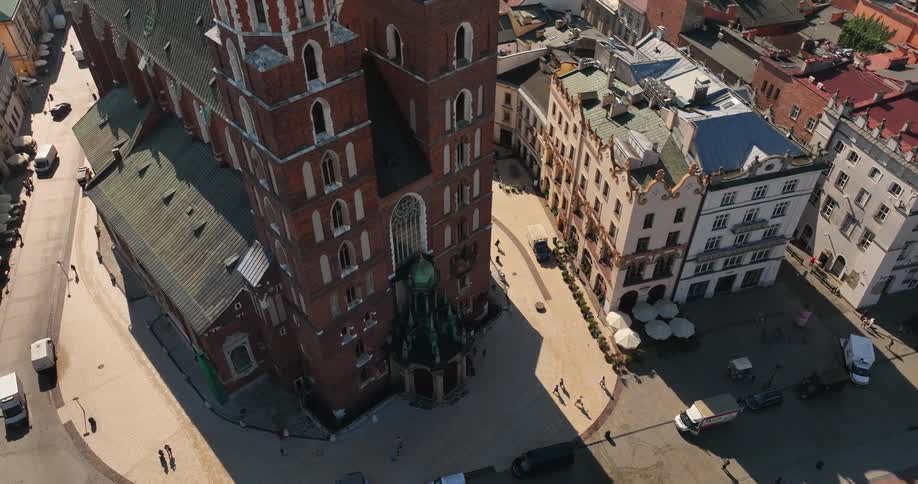 View from above with automobiles on the street and people walking on the sidewalks around buildings with old unusual architecture