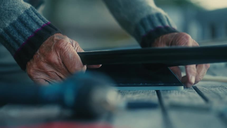 An elderly persons hands touching an object