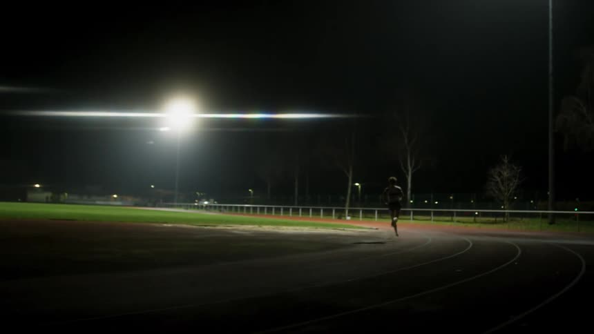 Female runner runs on running track at night