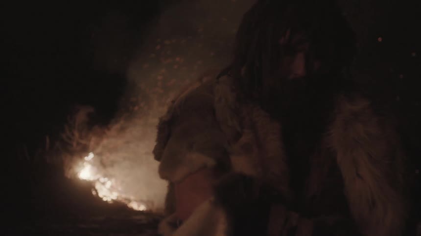 A man watches on at night as an area burns before him