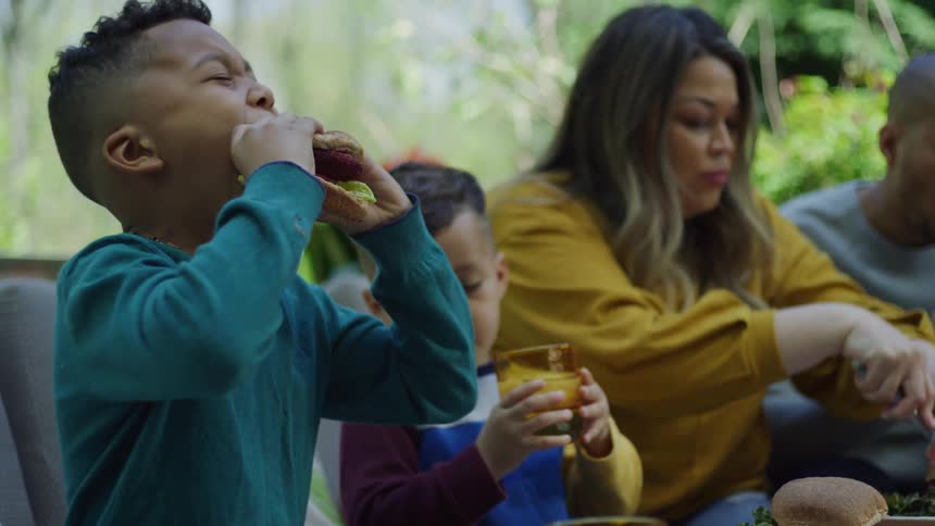 A family eats burgers on their patio