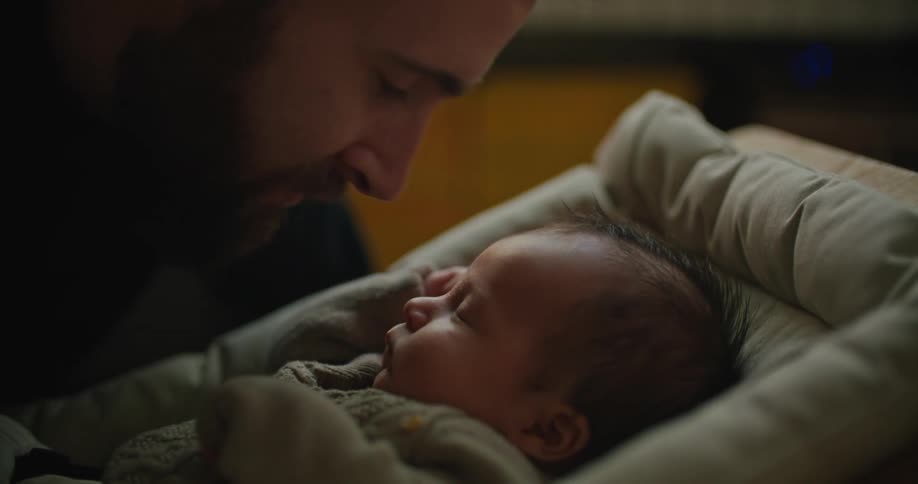 A father kisses his sleeping baby on the forehead
