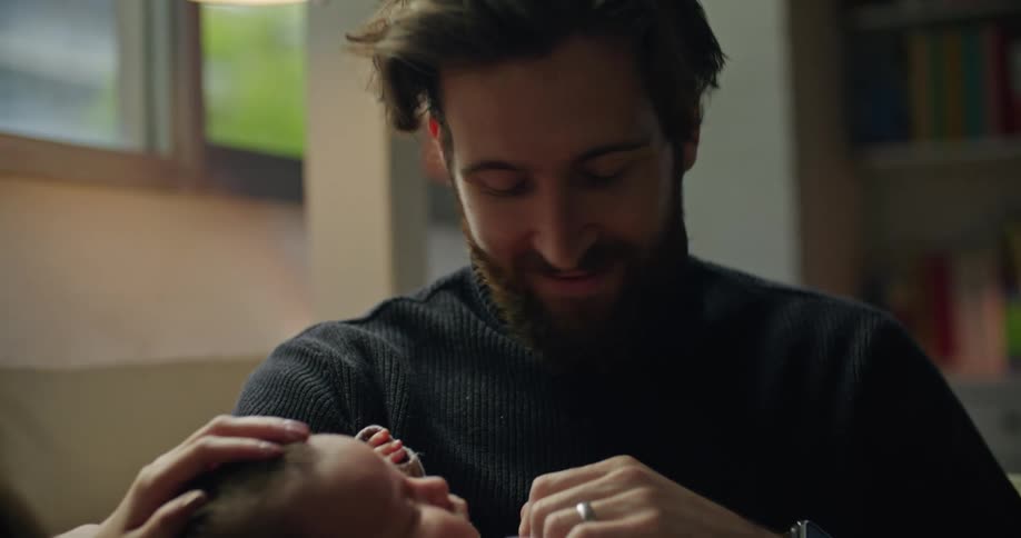 Parents smile and talk with each other as father holds baby