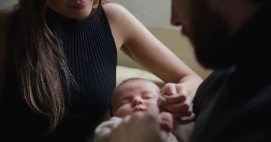 A man rocks his baby while his wife caresses the childs head