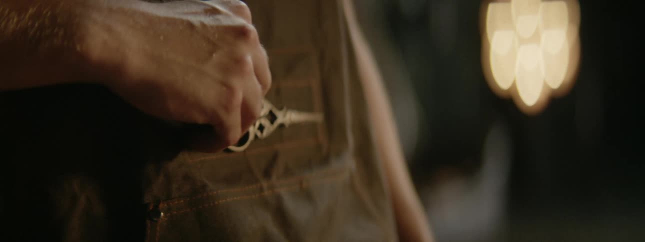 A tailor removes a pair of scissors from his apron