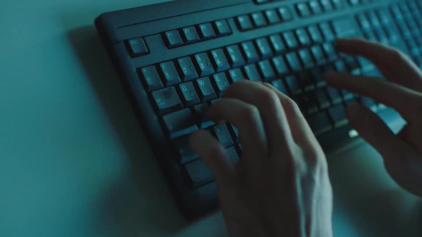 A person types on a keyboard lying on a desk