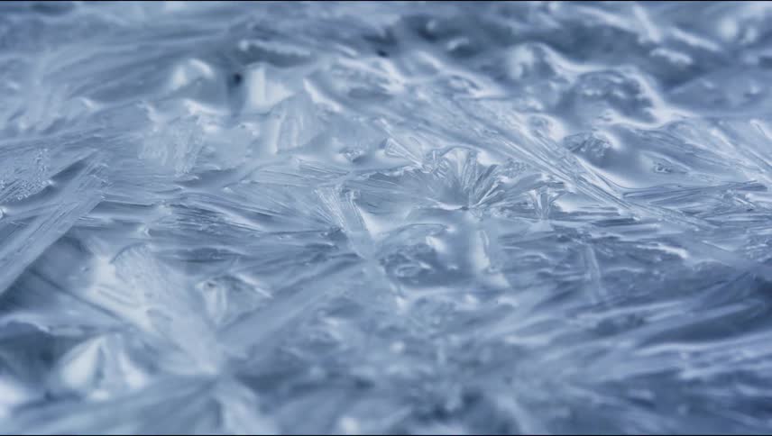 Translucent ice crystals spread to cover dark surface
