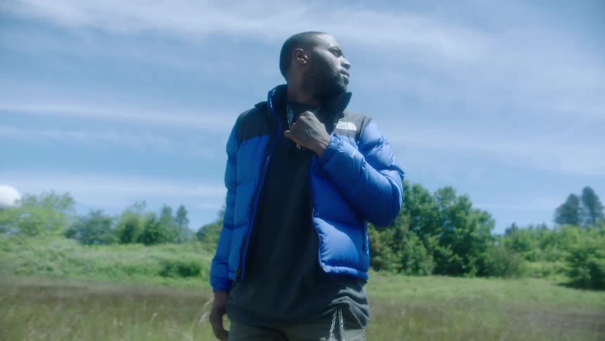 A man walks through a field with his hands in his pockets