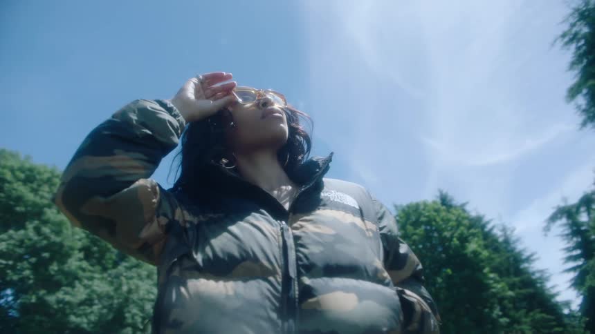 Young attractive woman wearing a jacket models for the camera on the grass