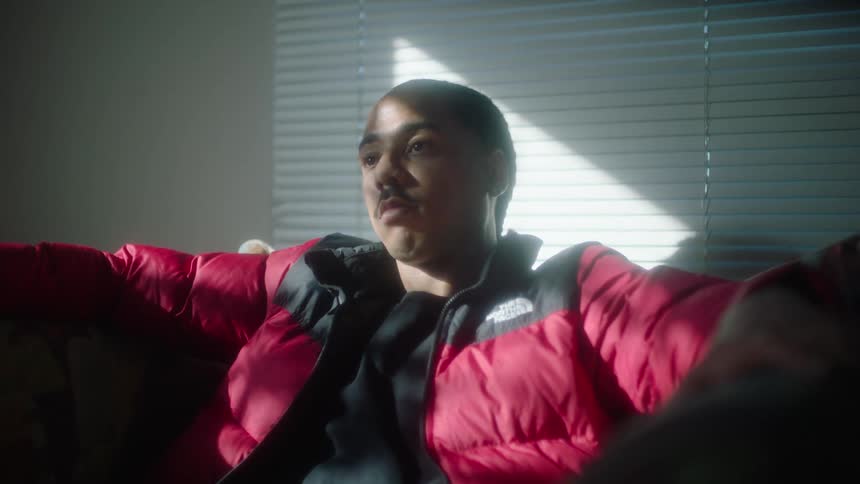 Man wearing a red jacket sitting on a couch in a room at morning