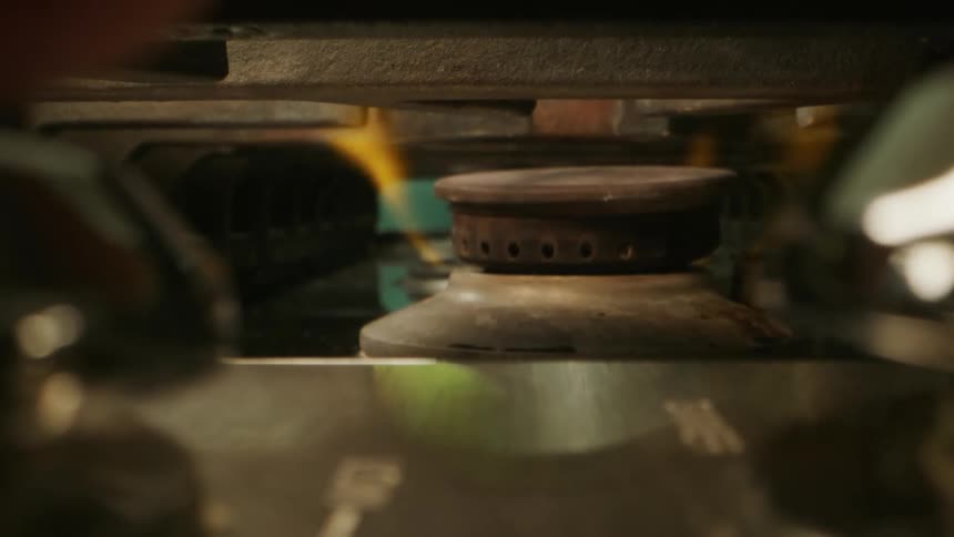 Close up of a person turning a knob on a stove to light up a burner