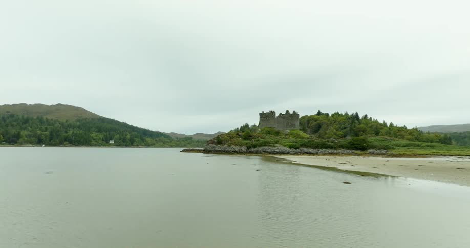 Aerial view of an abandoned castle in ruins on a small hill on the coast of a lake