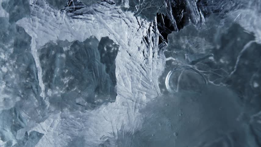 Close up of running water breaking up a sheet of ice crystals