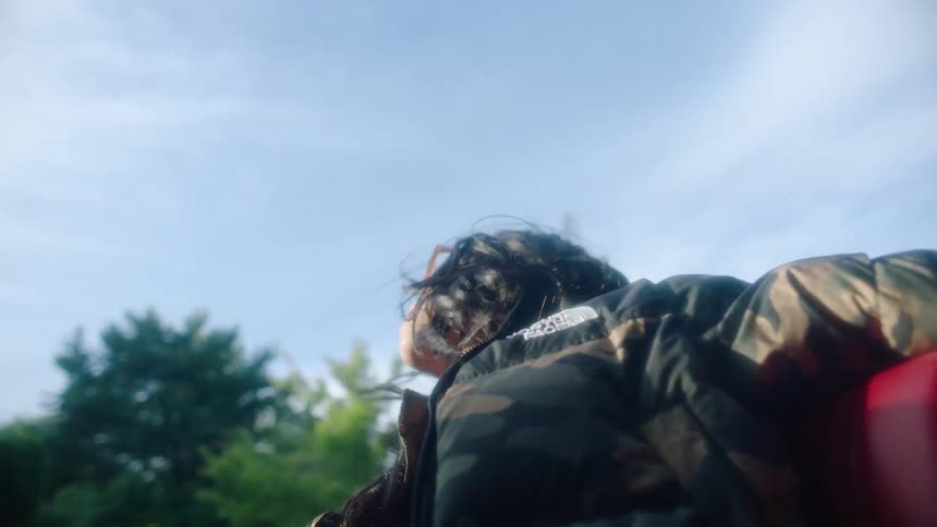 Young woman sitting on the back of a convertible car shakes her hair and looks at her phone