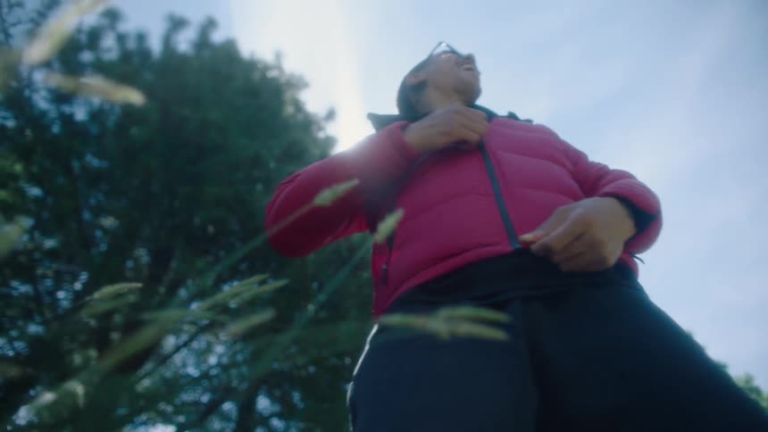 A man zips up his coat while standing outdoors
