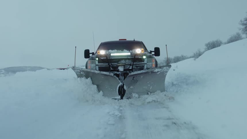 A pickup truck plows through a parking lot of thick snow