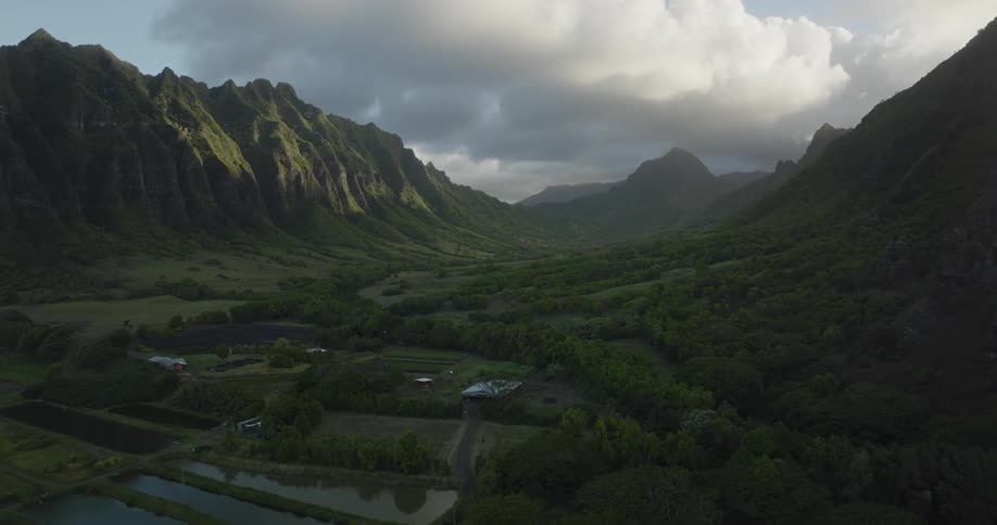 A farm is nestled in a valley running through large mountains