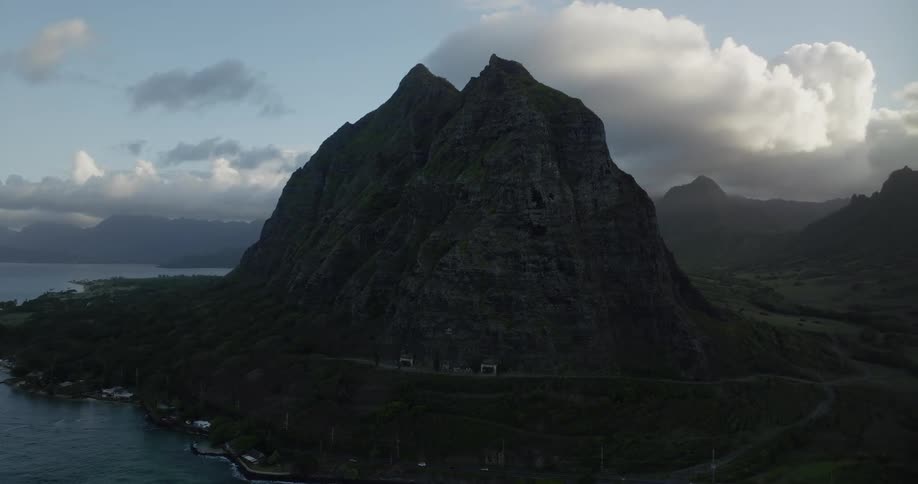 A smattering of homes sit below a tall summit along the coast