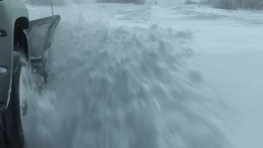 Close up of the tire of a pickup truck plowing through a thick layer of packed snow on a road in the countryside