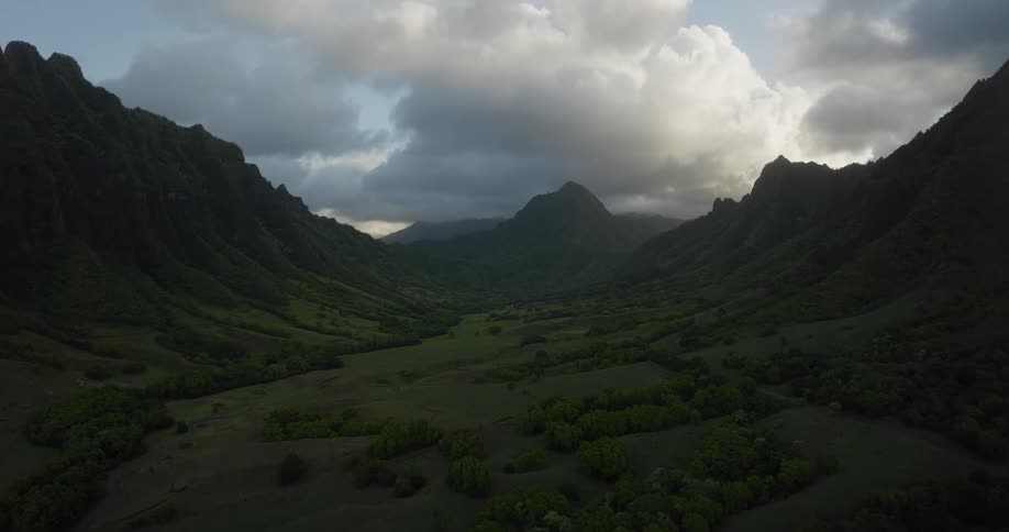 A lush green field sits below a bast canyon