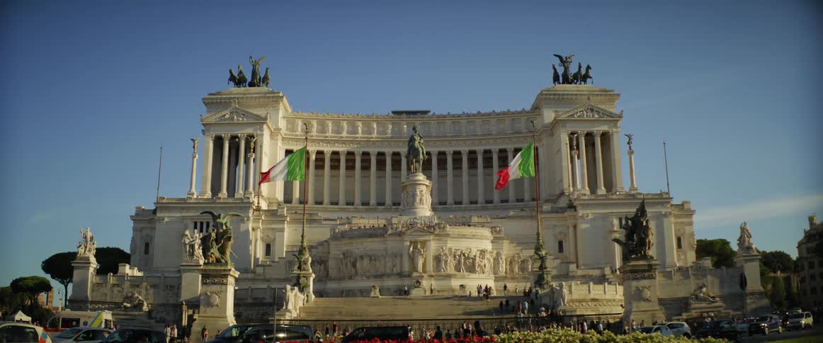 Tourists walking around the piazza venezia monument with its sculptures and columns