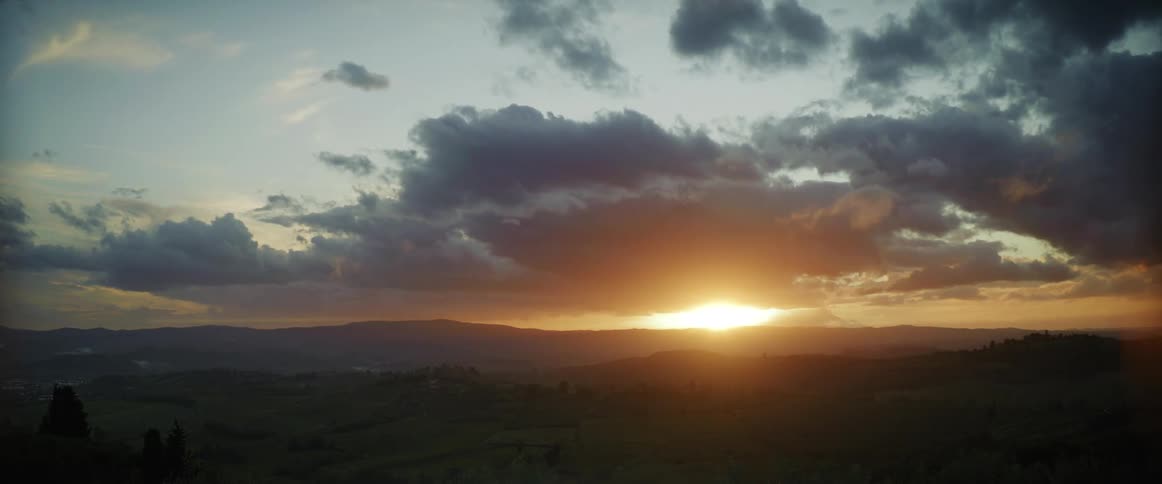 The sun sets over rolling hills