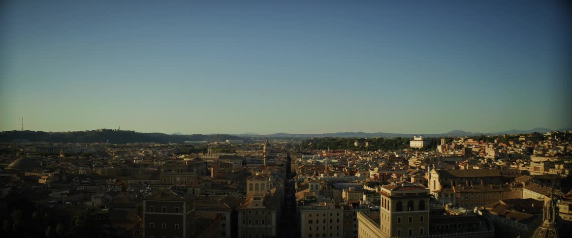 A sprawling old city with hills on the horizon on a sunny day