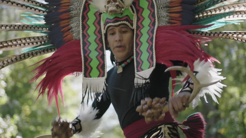 A man in a headdress dances around